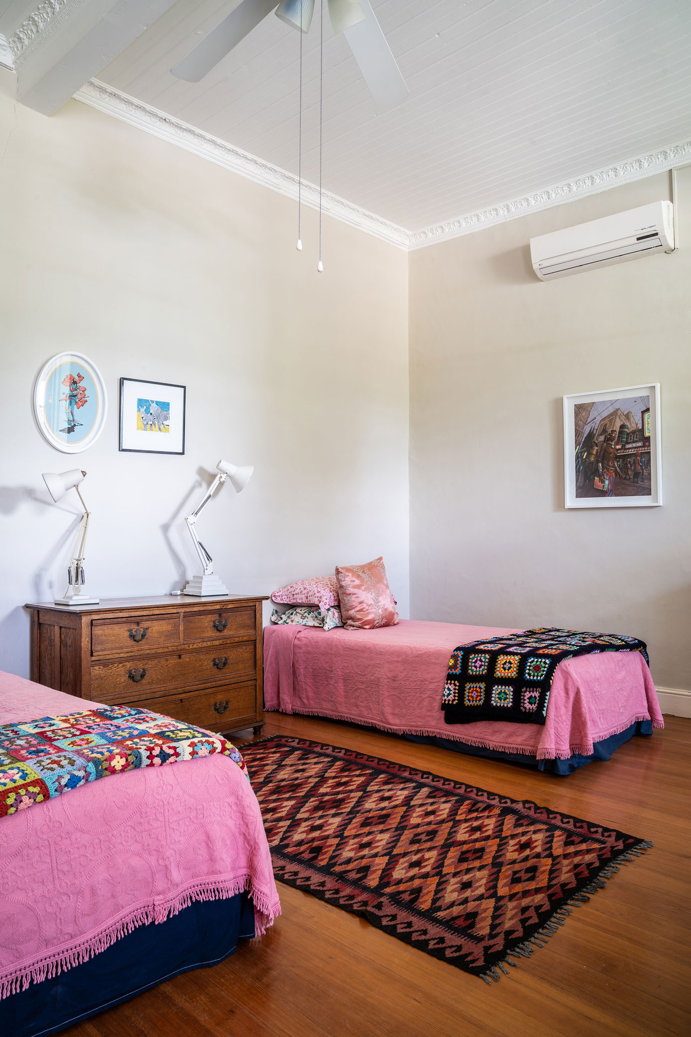 Pink bedroom with antique dresser and bold patterns and colours