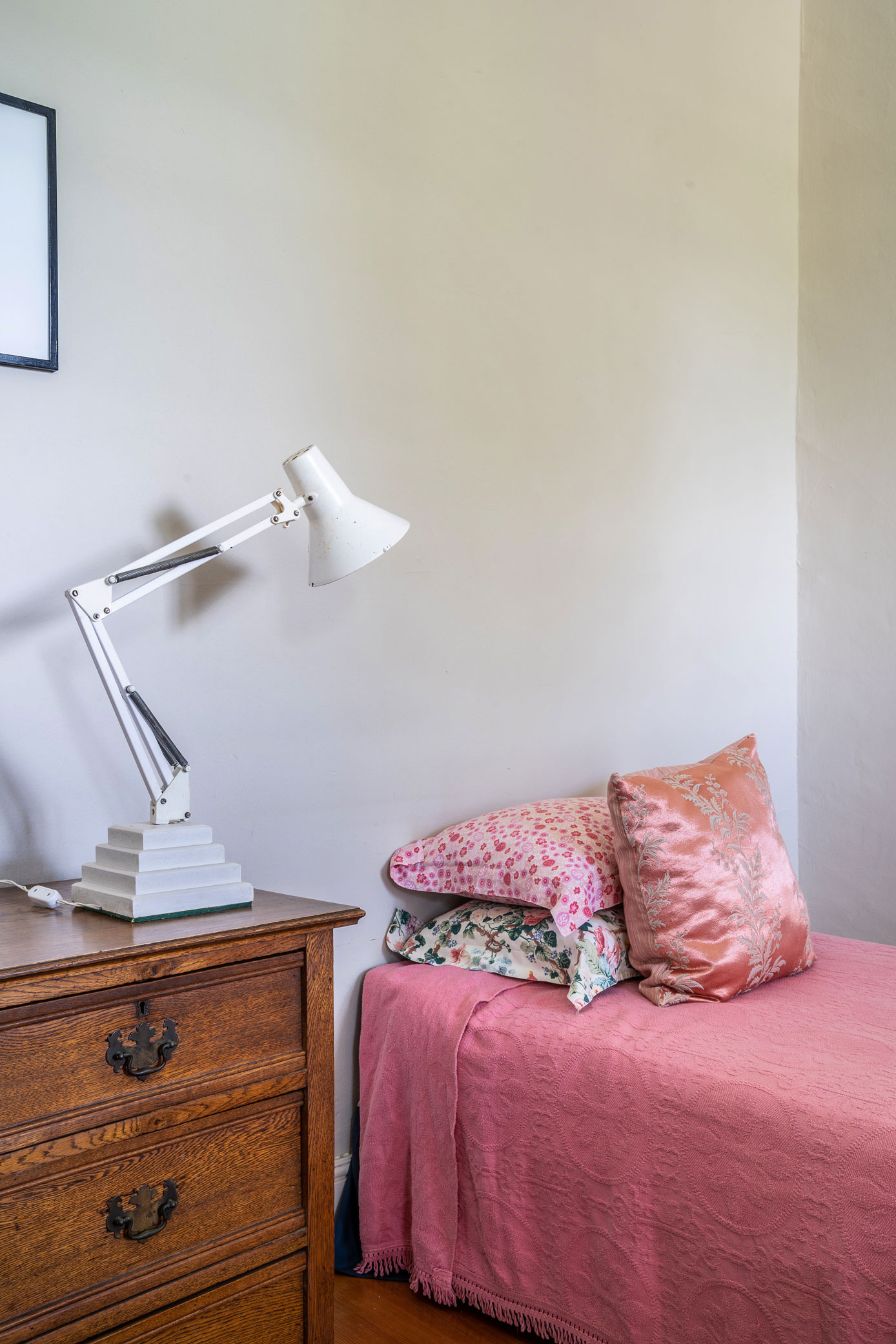 Pink bedroom with antique dresser and bold patterns and colours