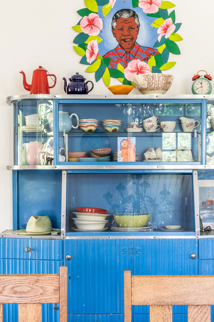 A blue vintage cabinet styled with colourful trinkets and South African paraphernalia